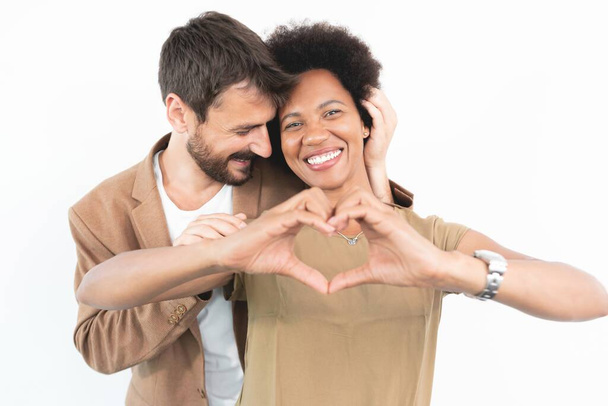 Romantic man embracing woman making heart shape with hands - Фото, изображение