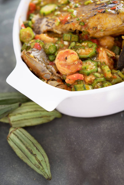 Sopa de Okra de frutos do mar ou sopa de Okra nigeriana cozida com camarões, caranguejo e peixe pronto para comer. Vi quiabo fresco são colocados ao lado.  - Foto, Imagem