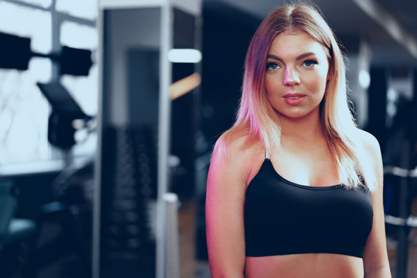 Young beautiful woman in sportswear in a gym - Фото, изображение