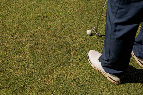 przycięty strzał profesjonalnego golfisty uderzającego piłkę na zielonym trawniku - Zdjęcie, obraz