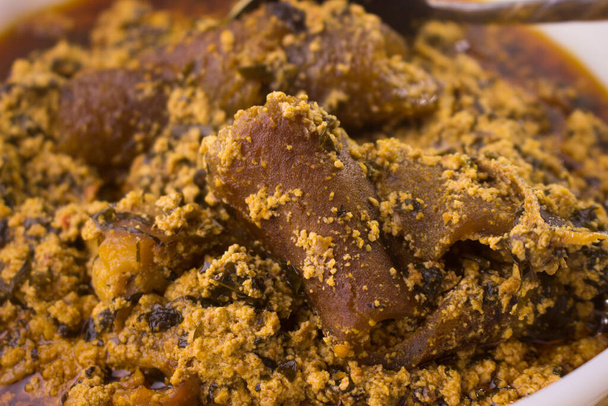 Vista de cerca de la deliciosa sopa nigeriana Egusi cocinada con carne variada y pescado seco, incluida la carne de kpomo o pomo - Foto, imagen