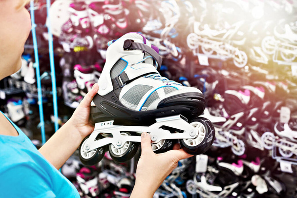 Woman chooses roller skates in sports shop - Фото, изображение