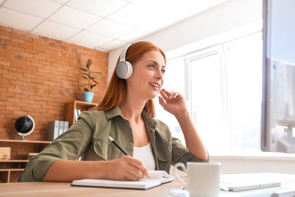 Woman with headphones working in office - Photo, Image