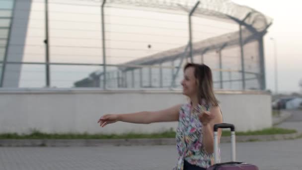 Мать встречает дочь рядом с терминалом аэропорта с распростертыми объятиями после долгой командировки - Кадры, видео