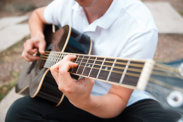 Nahaufnahme eines Mannes, der an einer akustischen Gitarre spielt - Foto, Bild