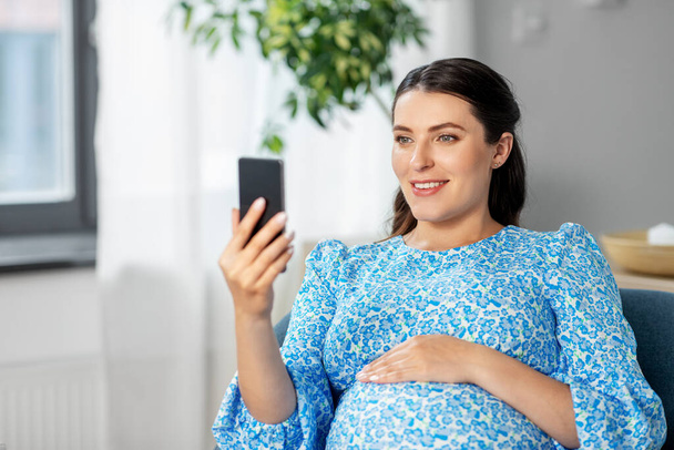 happy pregnant woman with smartphone at home - Photo, Image