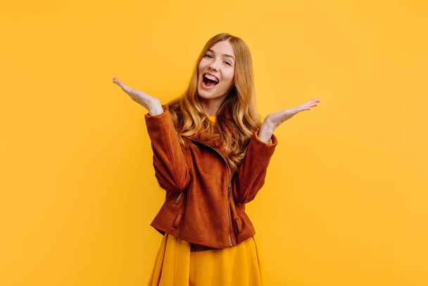 beautiful girl, in bright yellow dress and autumn jacket, showing emotion of joy, standing against isolated yellow background - Fotoğraf, Görsel