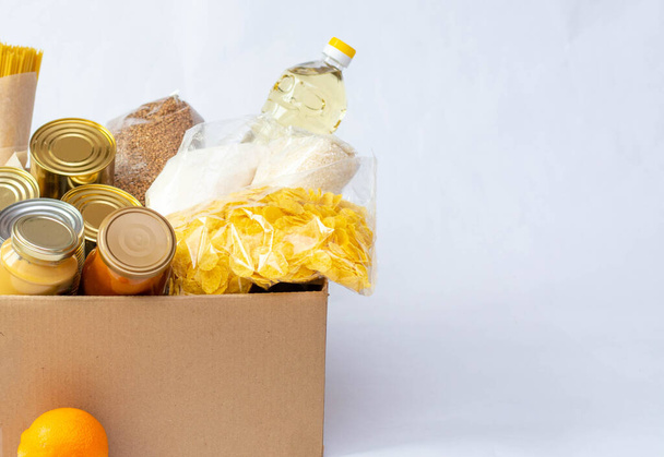 Various canned food, pasta and cereals in a cardboard box. Food donations or food delivery concept. - 写真・画像