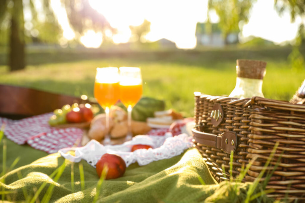 Basket with tasty food and drink for romantic picnic in park - Photo, Image