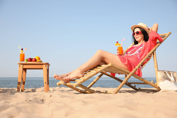 Beautiful woman in red dress resting on beach - Fotoğraf, Görsel