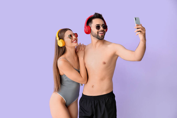 Młoda para ze słuchawkami i telefonem komórkowym na kolorowym tle - Zdjęcie, obraz