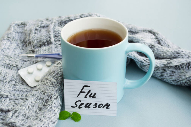 Soğuk algınlığı ve grip. Sıcak çay, nane, termometre ve açık mavi arka planda haplı bardak. Virüsün tedavisi ve önlenmesi - Fotoğraf, Görsel