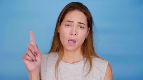 Schöne selbstbewusste Frau im grauen T-Shirt gestikuliert mit erhobenem Zeigefinger - Filmmaterial, Video