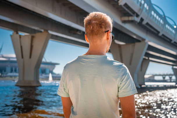 Photo from the back of a young man against the background of metal structures of the Western high-speed diameter automobile bridge in St. Petersburg - Photo, Image
