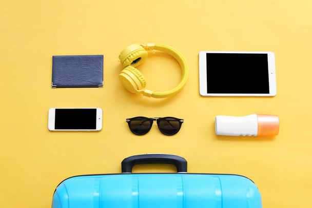 Packed suitcase with beach accessories and devices on color background. Travel concept - Фото, изображение