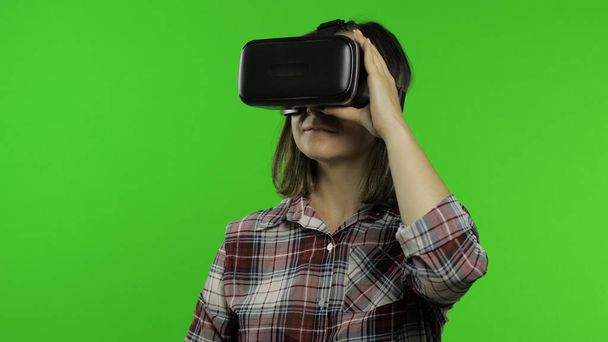 Νεαρή κοπέλα που χρησιμοποιεί κράνος VR app για να παίξει παιχνίδι προσομοίωσης. Γυναίκα βλέποντας εικονική πραγματικότητα 3D βίντεο - Φωτογραφία, εικόνα