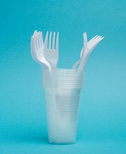 gobelets jetables en plastique, fourchettes sur fond bleu, ensemble pique-nique - Photo, image