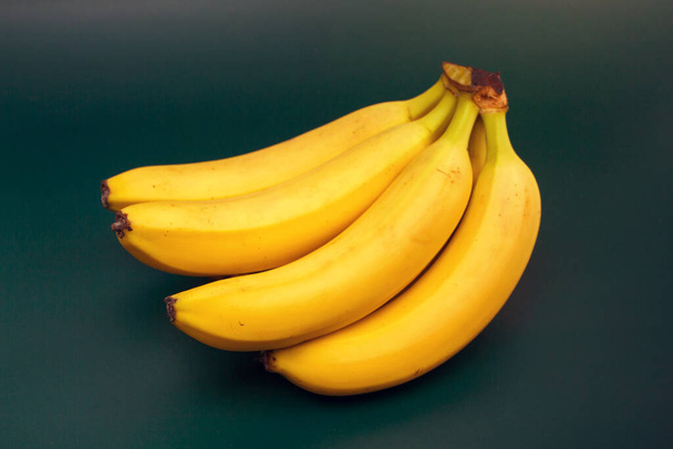 egy csomó banán sötét zöld háttérrel - Fotó, kép