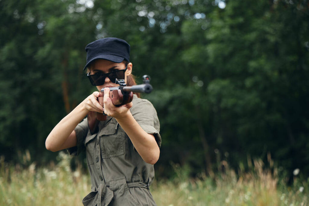 Militar mujer sostener un arma en las manos gafas de sol con el objetivo de aire fresco  - Foto, Imagen