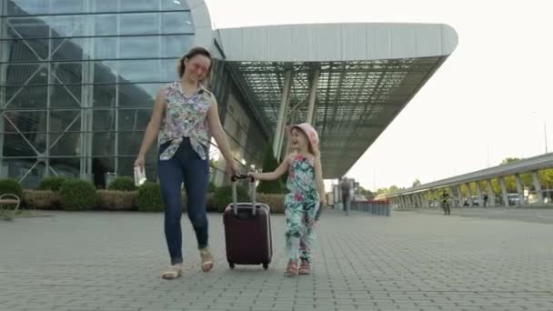 Mother and daughter walking from airport. Woman carrying suitcase bag. Child and mom after vacation - Footage, Video