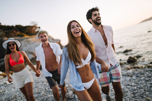 Group of happy friends having fun on the beach under sunset on vacation - Foto, Imagem