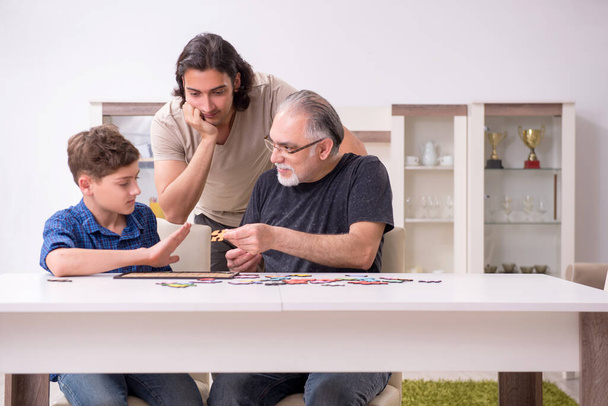 Three generations of family playing jigsaw puzzle game - Valokuva, kuva