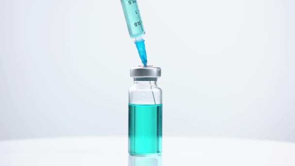 Glass medicine vial with blue liquid and syringe. - Footage, Video