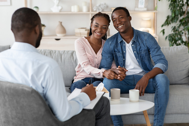 効果的な結婚療法。幸せなアフリカのカップル座っています上のカウンセラーオフィス - 写真・画像