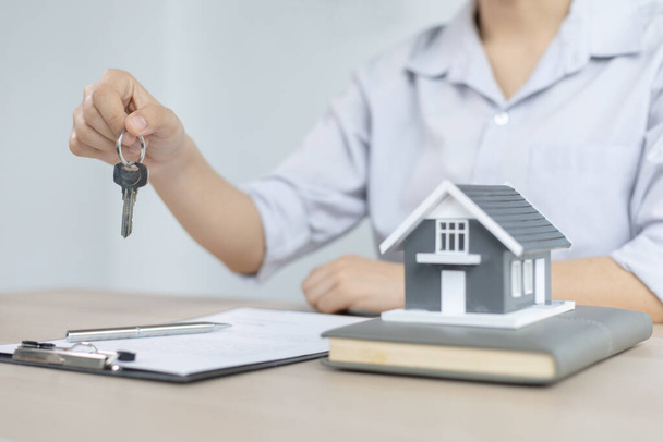 不動産エージェントは、クライアントに送信するための鍵を保持し、顧客に住宅販売契約と住宅保険に署名するための条件を提供しています,住宅販売と住宅保険の概念. - 写真・画像