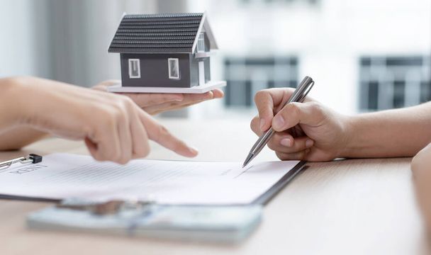 Home agent or real estate agent allows clients to sign a home purchase contract and hand over a home to the client, Home sales and home insurance concept. - Photo, Image
