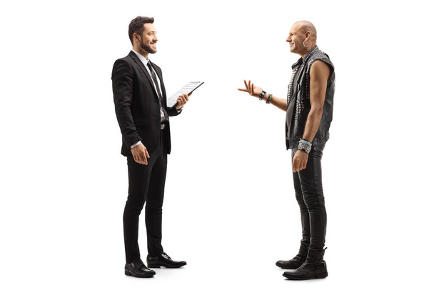 Full length profile shot of a businessman holding a clipboard and talking to a punk rocker guy isolated on white background - Valokuva, kuva