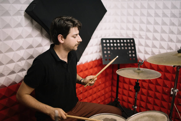 Man recording music on drum set in studio - Foto, afbeelding