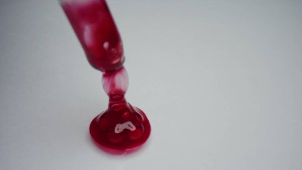Gota de sangre con pipeta sobre fondo blanco. Investigador agitando sangre
 - Foto, Imagen