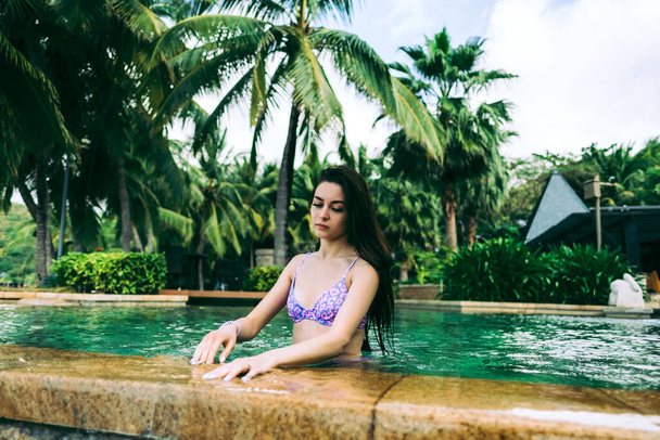 Houkutteleva valkoihoinen nuori nainen kesärantalomalla rentoutumassa ylellisessä kylpylähotellissa uima-altaassa. Terveellinen elämäntapa, perheen matkustustausta. Trooppisen saaren kiertue. Laadukas kuva - Valokuva, kuva