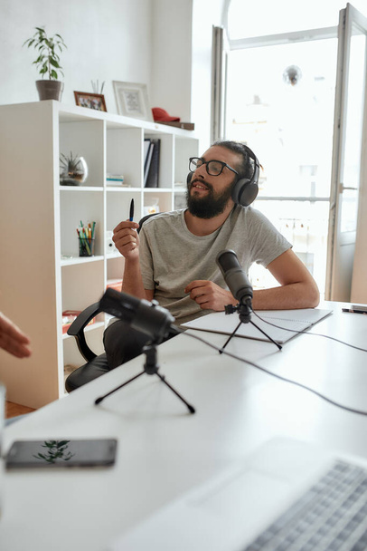 Male blogger, man in headphones listening to interlocutor while talking, recording conversation, interview for video blog - Fotoğraf, Görsel