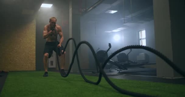 Άνδρας αθλητής γυμνάζεται με σχοινιά σε παλιό κτίριο. Αθλητής σε προπόνηση με σχοινιά κοντά στον καθρέφτη. Σκοινί μάχης - Πλάνα, βίντεο