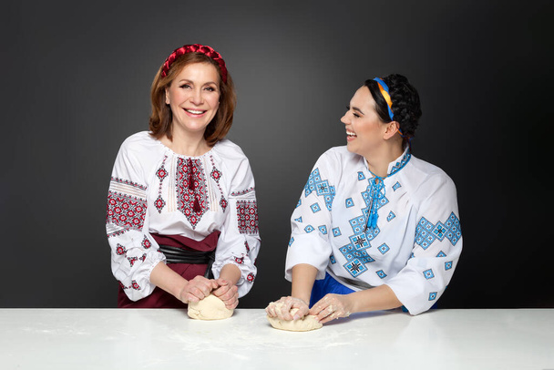 Dwie dorosłe kobiety w tradycyjnym ukraińskim stylu. Gotowanie ukraiński varenyky. Seria. - Zdjęcie, obraz