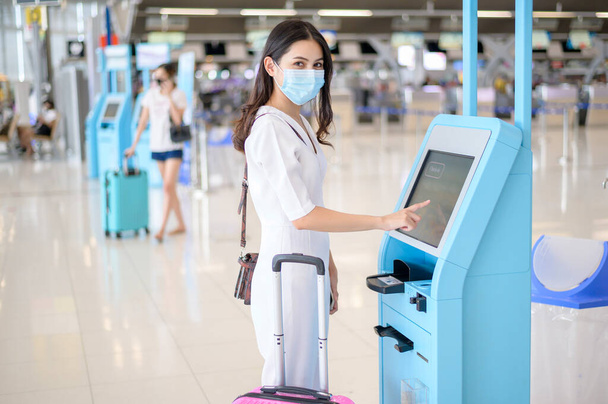 A traveller woman is wearing protective mask in International airport, travel under Covid-19 pandemic, safety travels, social distancing protocol, New normal travel concept . - Fotoğraf, Görsel