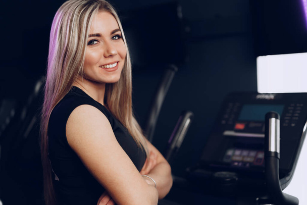 Attractive young blonde woman exercising on cardio training apparatus - Fotó, kép