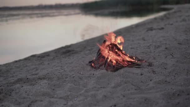 Bonfire branden op de oever van de rivier bij zonsondergang, Ob rivier, Siberië, - Video