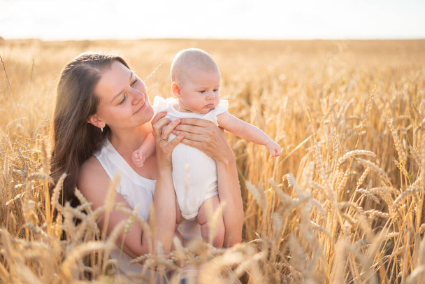 Beautiful young mother and her daughter baby girl at the wheat field in sunny day in Czech republic - Foto, Imagen