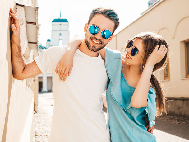 Portrait of smiling beautiful woman and her handsome boyfriend. Woman in casual summer jeans dress. Happy cheerful family. Female having fun. Couple posing on the street background in sunglasses - Photo, Image