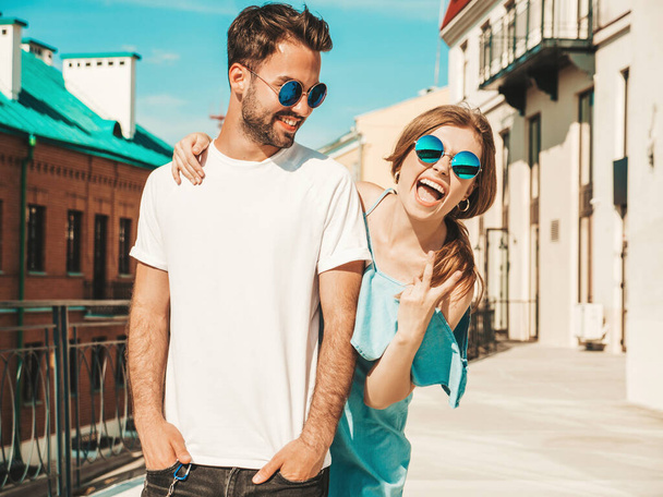 Portrait of smiling beautiful woman and her handsome boyfriend. Woman in casual summer jeans dress. Happy cheerful family. Female having fun. Couple posing on the street background in sunglasses - Zdjęcie, obraz