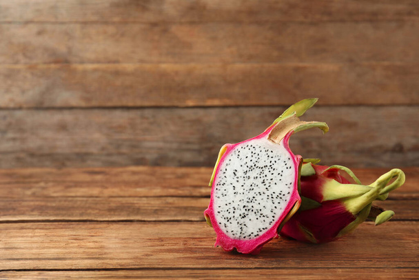 Delicious cut and whole dragon fruits (pitahaya) on wooden table. Space for text - Fotografie, Obrázek