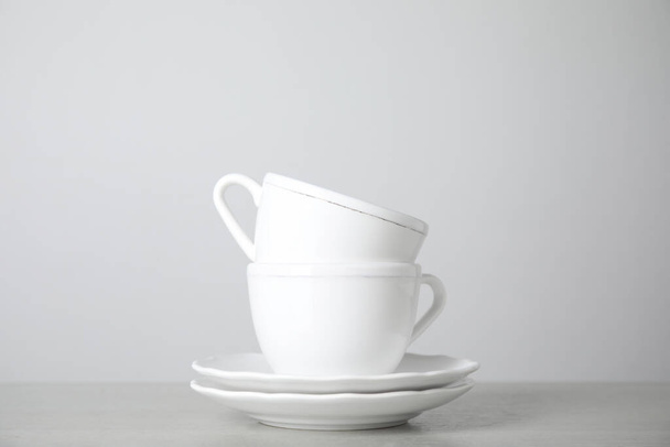 Ceramic saucers and cups on table against white background - Photo, Image