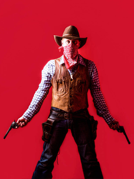 Bandito americano mascherato, uomo occidentale con cappello. Un uomo con un cappello da cowboy e una pistola. Ovest, armi. Ritratto di cowboy. owboy con arma su sfondo rosso - Foto, immagini