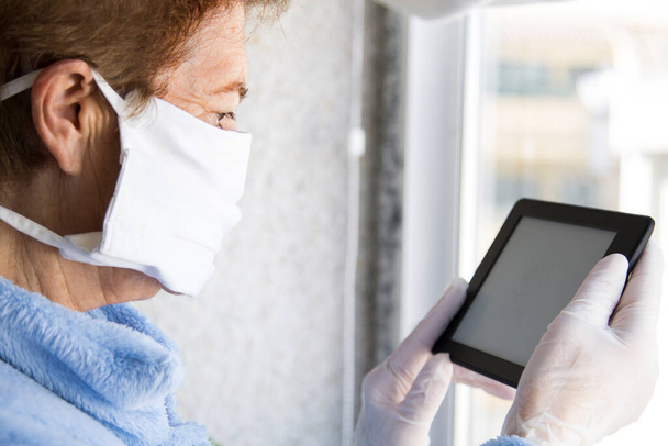 senior person with medical face mask and gloves and using tablet at home. quarantine. Corona Virus health concept ordering products online - Foto, Imagen