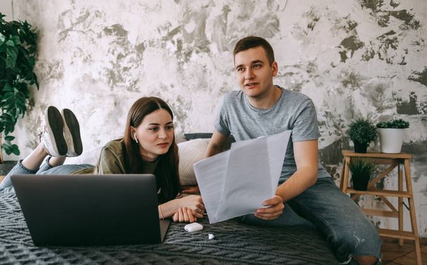 Coworkers discussing project and using laptop together, watching paper documents. Business colleagues together in cozy office space. Partnership or consulting concept. High quality photo - Фото, зображення