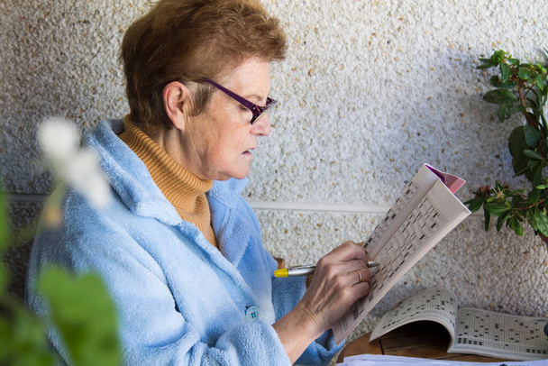 senior woman doing crossword puzzles or hobbies sitting - Photo, image