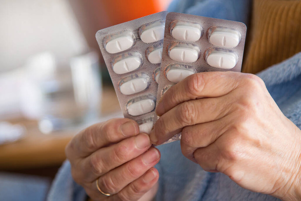 senior woman holding preventive pills tablet in hand for infections, viruses and diseases - 写真・画像